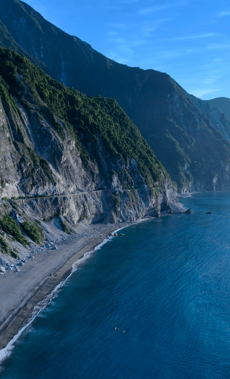 Heren Beach at dusk in Hualien — green-clad mountains plunging into the Pacific, gray pebble shore, turquoise water