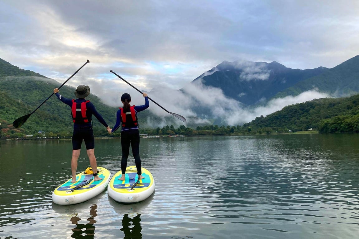 情侶背影各站一塊 SUP 板牽手舉槳, 鯉魚潭雲霧繚繞山景