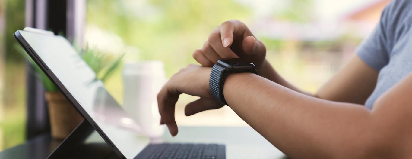 Checking a smartwatch beside a laptop
