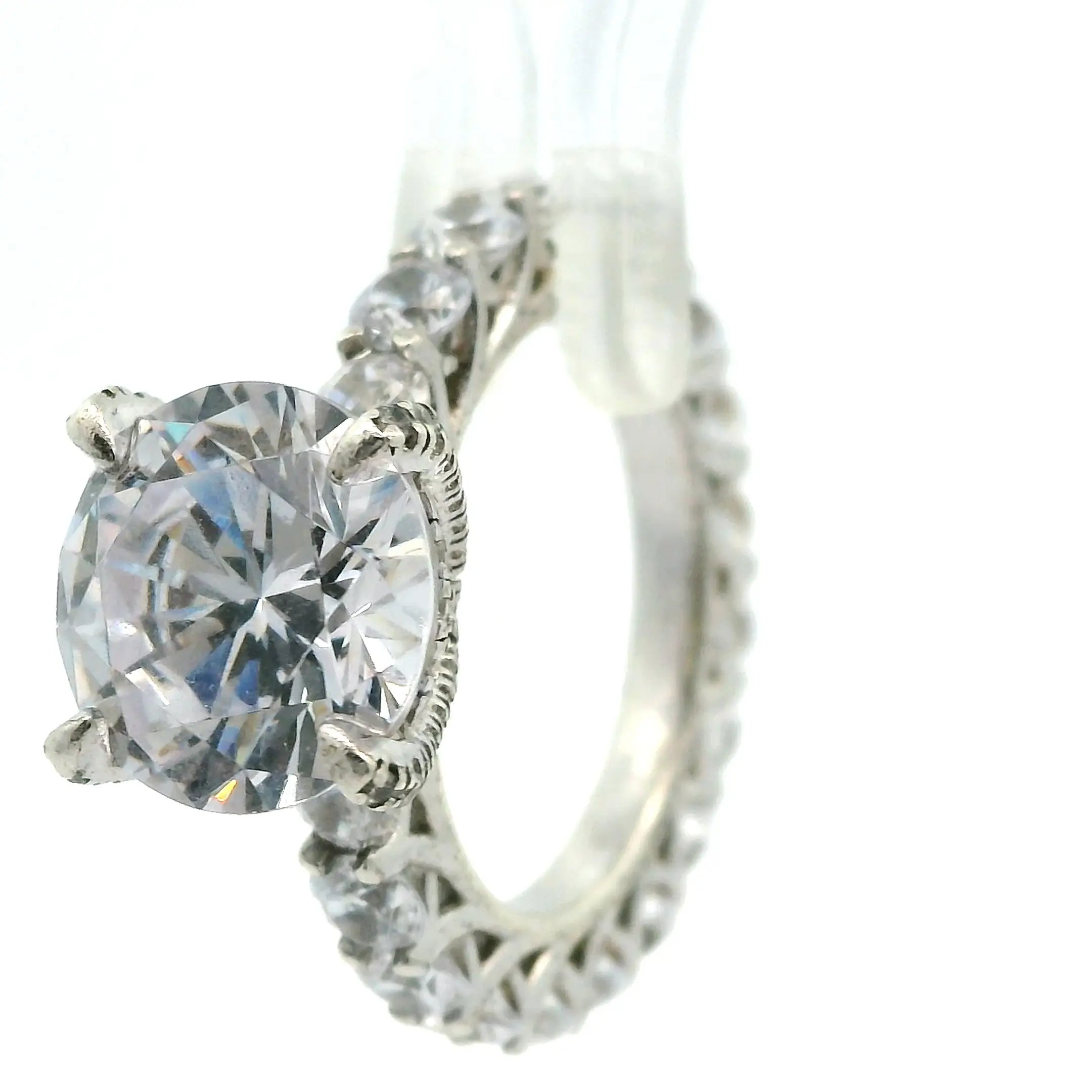 A diamond ring accented with small diamonds on the side, photographed on a white background