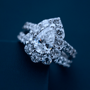 A pear-shaped diamond ring with halo setting and diamond-accented split side