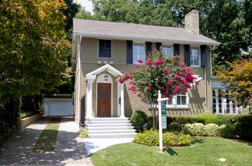 A two-story, beige home with a dark wood door and dark grey shutters in Sherwood Forest neighborhood in Atlanta.