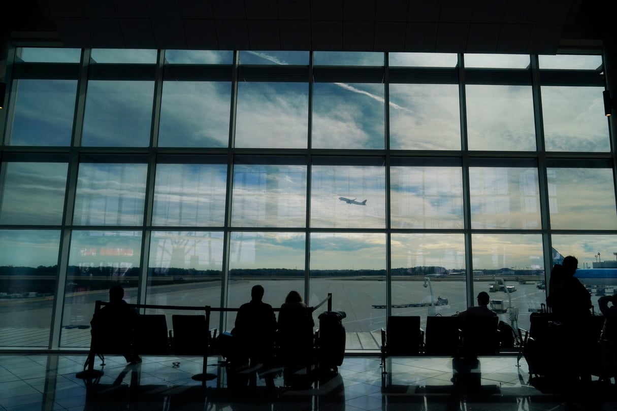 Travelers watch through a window as a plane takes off from Hartsfield-Jackson Atlanta International Airport in Atlanta.