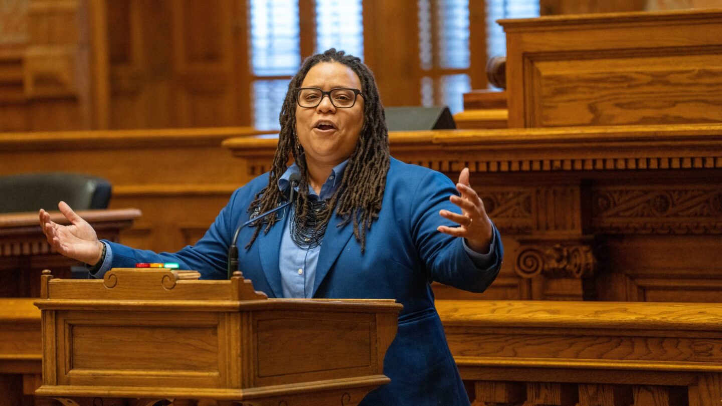 State Sen. Kim Jackson speaks at a lectern in a bright blue blazer.