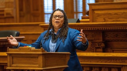 State Sen. Kim Jackson speaks at a lectern in a bright blue blazer.