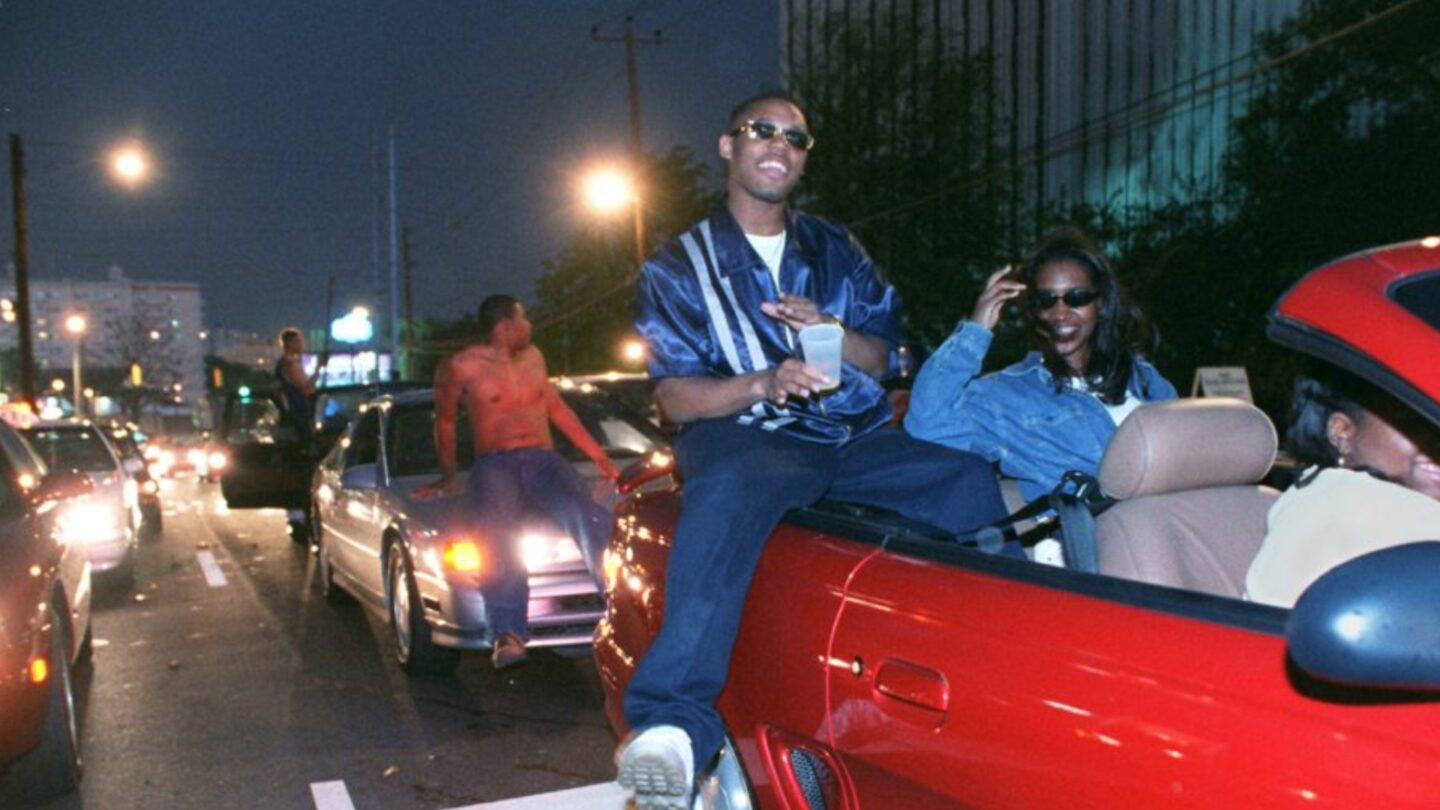 College kids sitting on cars in traffic