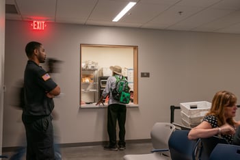 A person stands at a window to receive mail.