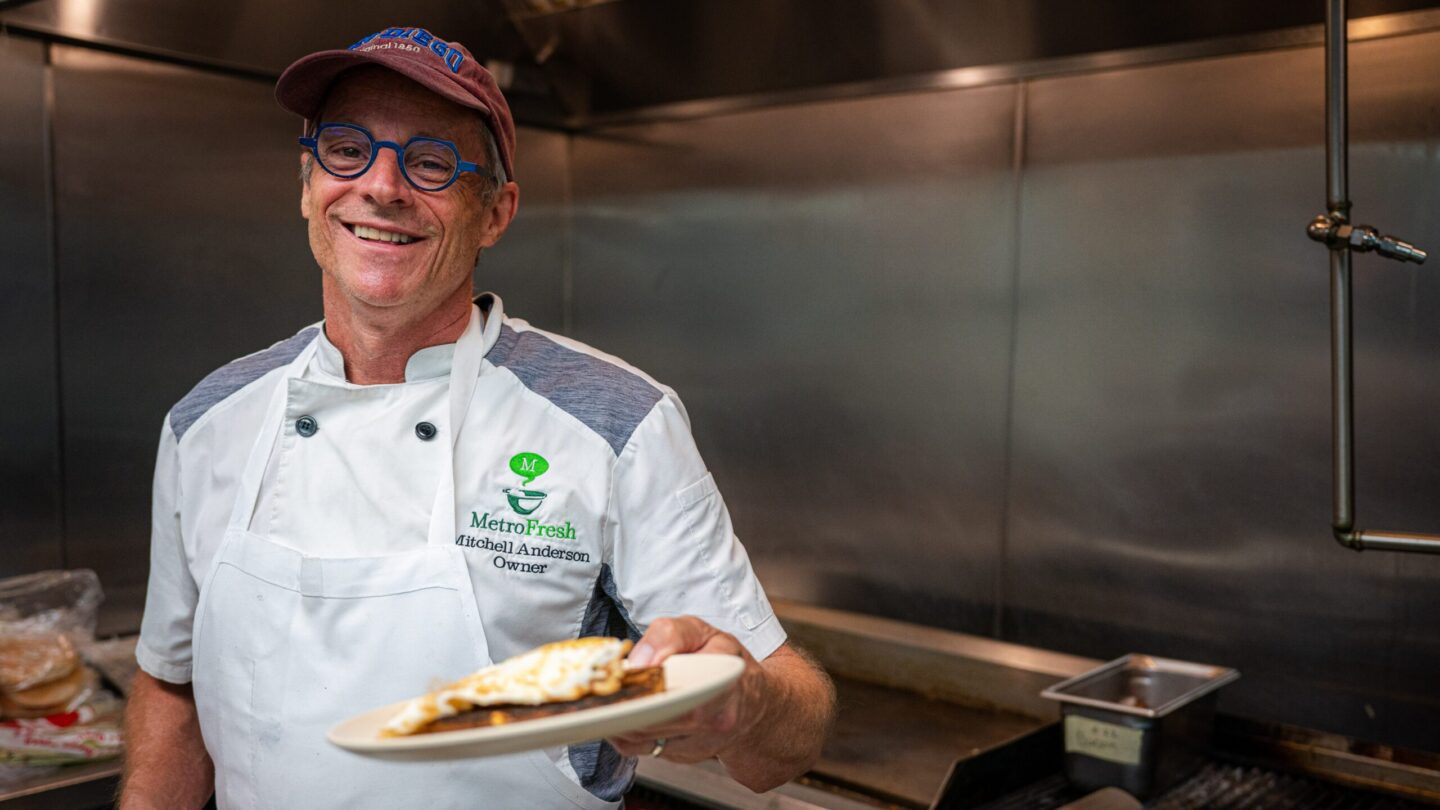 Man in kitchen holding plate of pizza