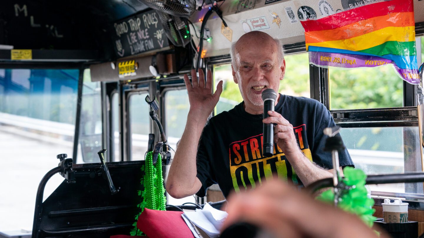 Man with Microphone and pride flag inside bus