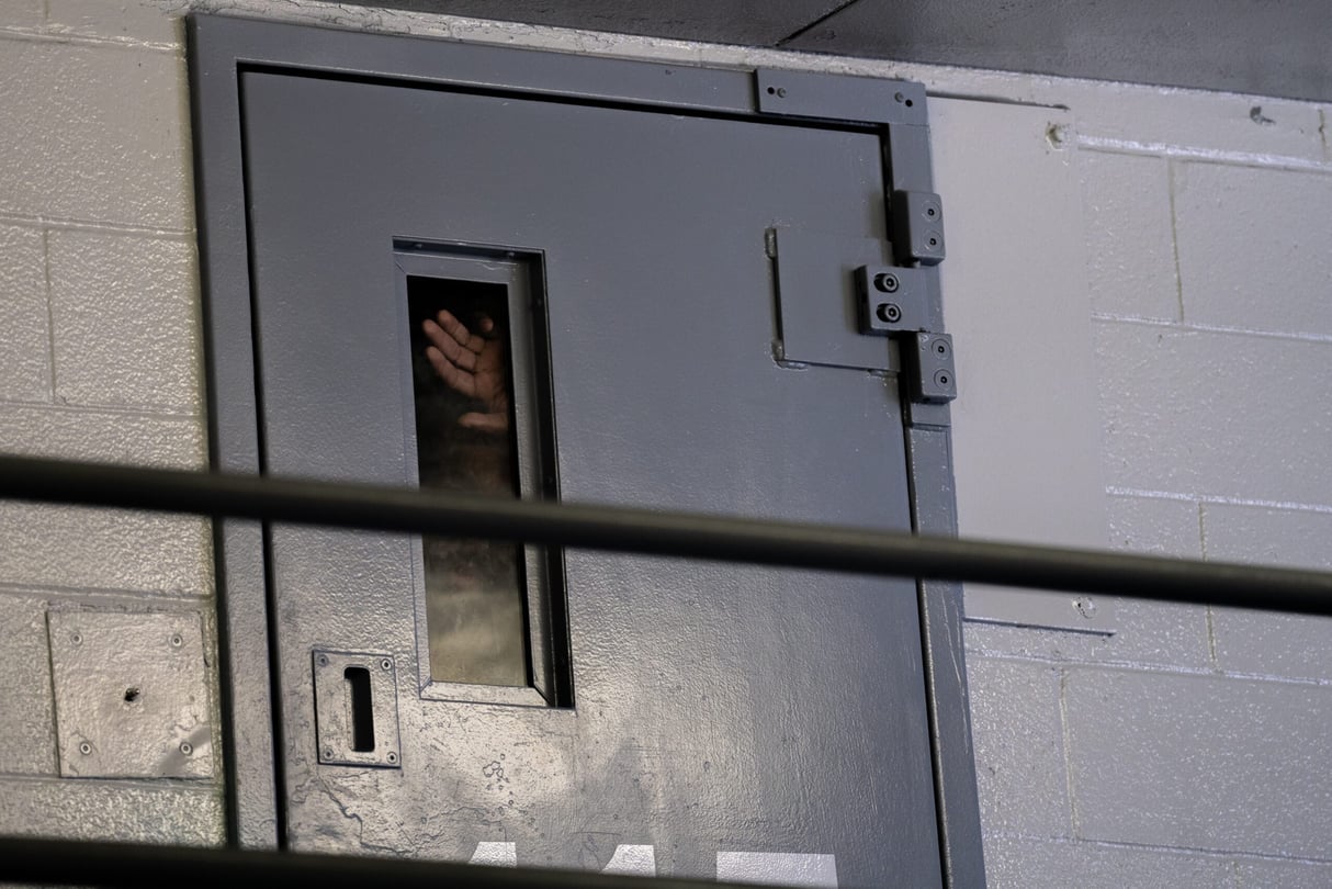 A hand presses against the cell window inside a dorm at the Fulton County Jail.