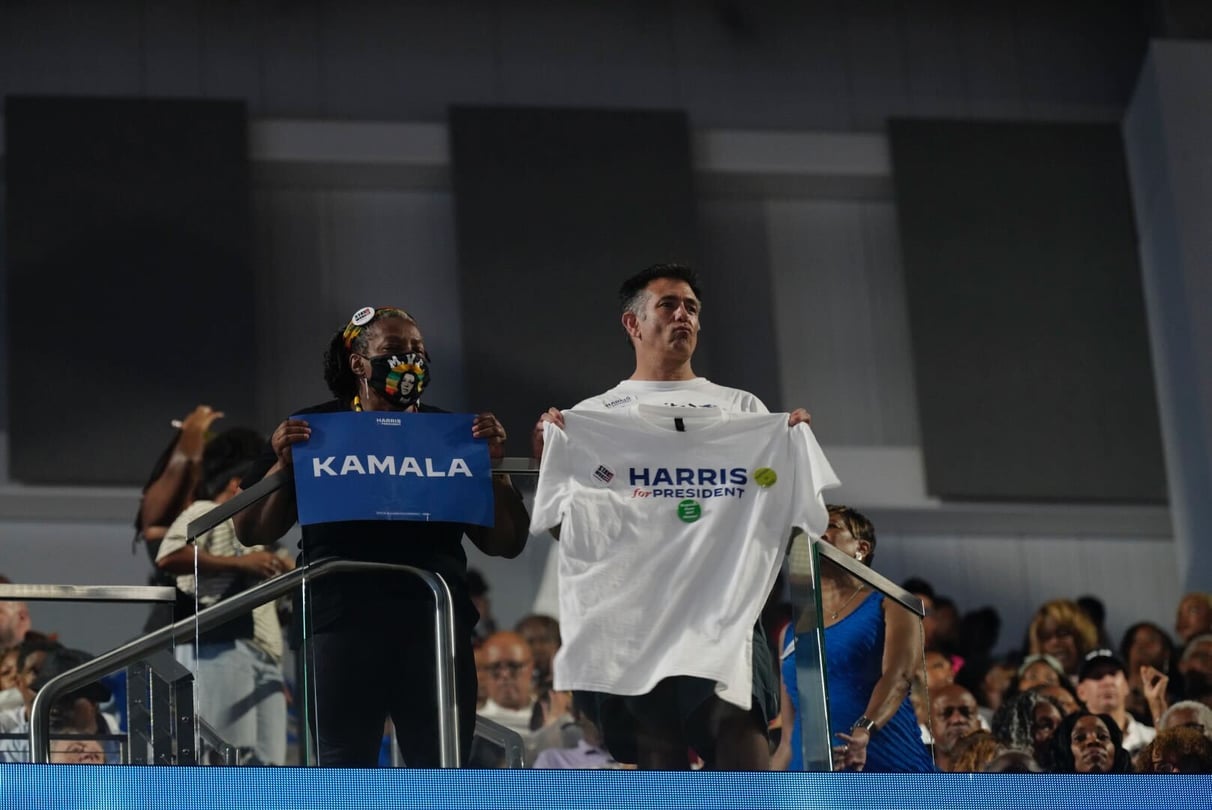 Attendees at Kamala Harris's campaign rally in Atlanta on July 30, 2024, hold up a sign and t-shirt that spell out the presumptive nominee's name.