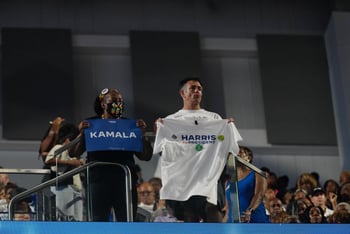 Attendees at Kamala Harris's campaign rally in Atlanta on July 30, 2024, hold up a sign and t-shirt that spell out the presumptive nominee's name.