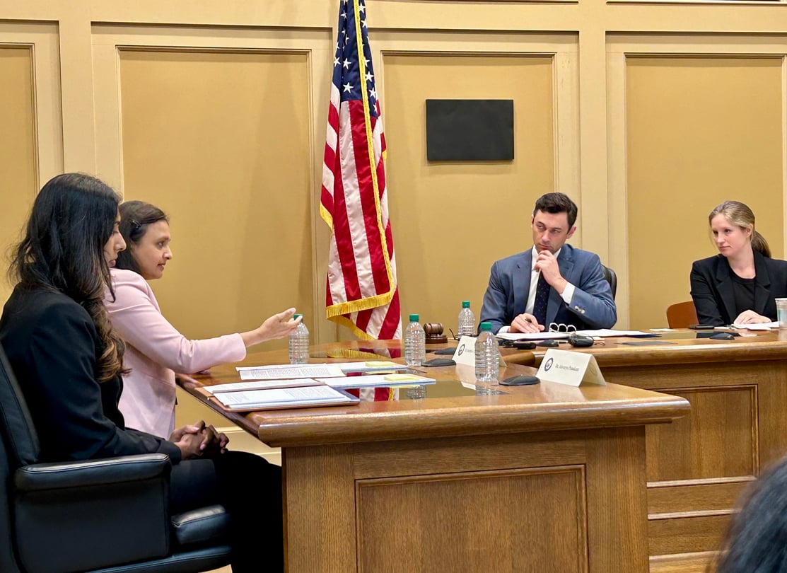 U.S. Sen. Jon Ossoff listens to testimony from physicians at a Senate subcommittee field hearing in Decatur. An American flag stands in the background of the hearing room.