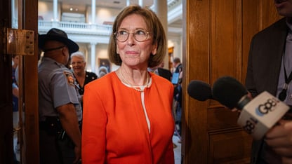 A woman wearing a bright orange outfit walks through wooden doors