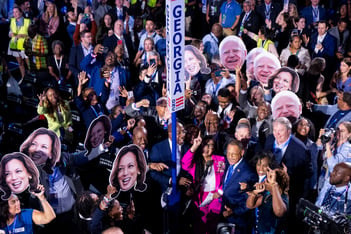 A crowd of Georgia delegates hold up cardboard cutouts of Kamala Harris and Tim Walz at the Democratic National Convention.