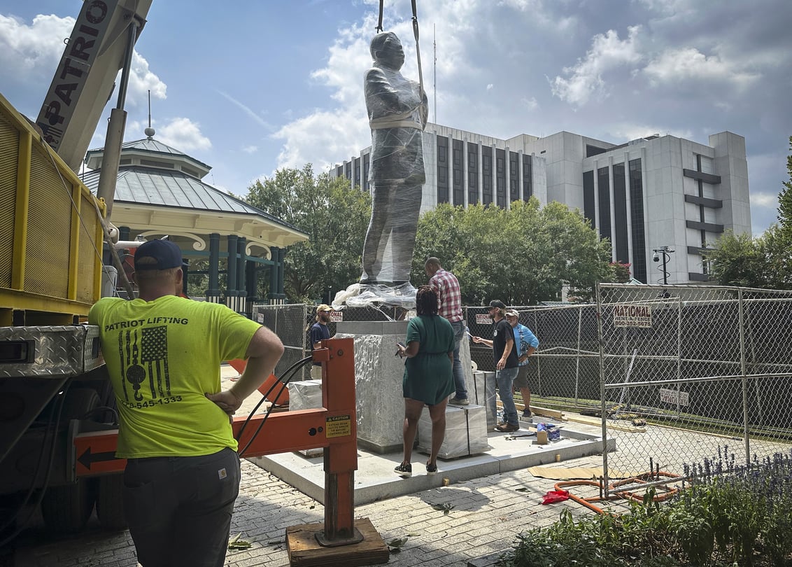 A large lift installs a statue of late civil rights leader and politician Congressman John Lewis.
