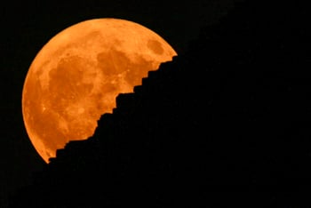 An orange supermoon rises behind the Giza Pyramids.