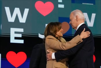 Joe Biden and Kamala Harris embrace in front of a backdrop at the Democratic National Convention.