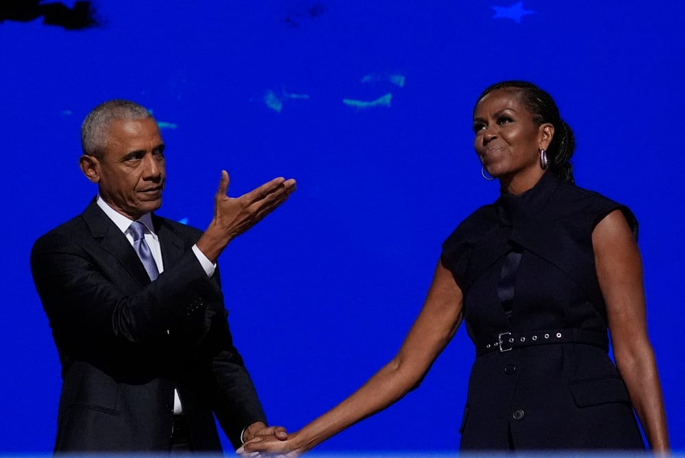 Barack Obama holds Michelle Obama's hand at the 2024 Democratic National Convention in Chicago after her speech.