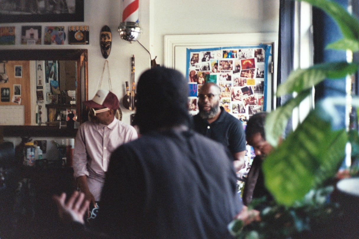 At the barbershop, Ernest Hood sits on the left, Javon Lee second from the left, Carlos York sits second on the right, and Devron Barrett is on the far right.