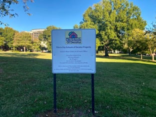 A sign saying This is City Schools of Decatur Property on a green field.