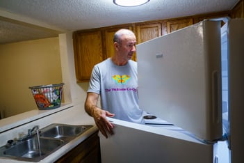 A man looks through an open fridge.