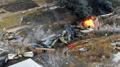 An overhead shot of several trains derailed and burning up in smoke.