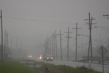 Cars drive through a thick fog outside of New Orleans ahead of Hurricane Francine