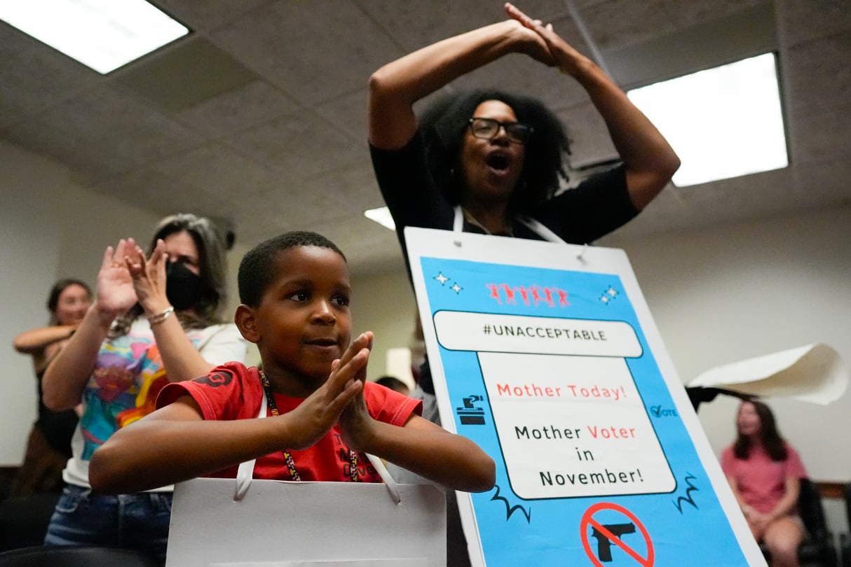 Parents and children raise their hands, carrying signs around their necks.