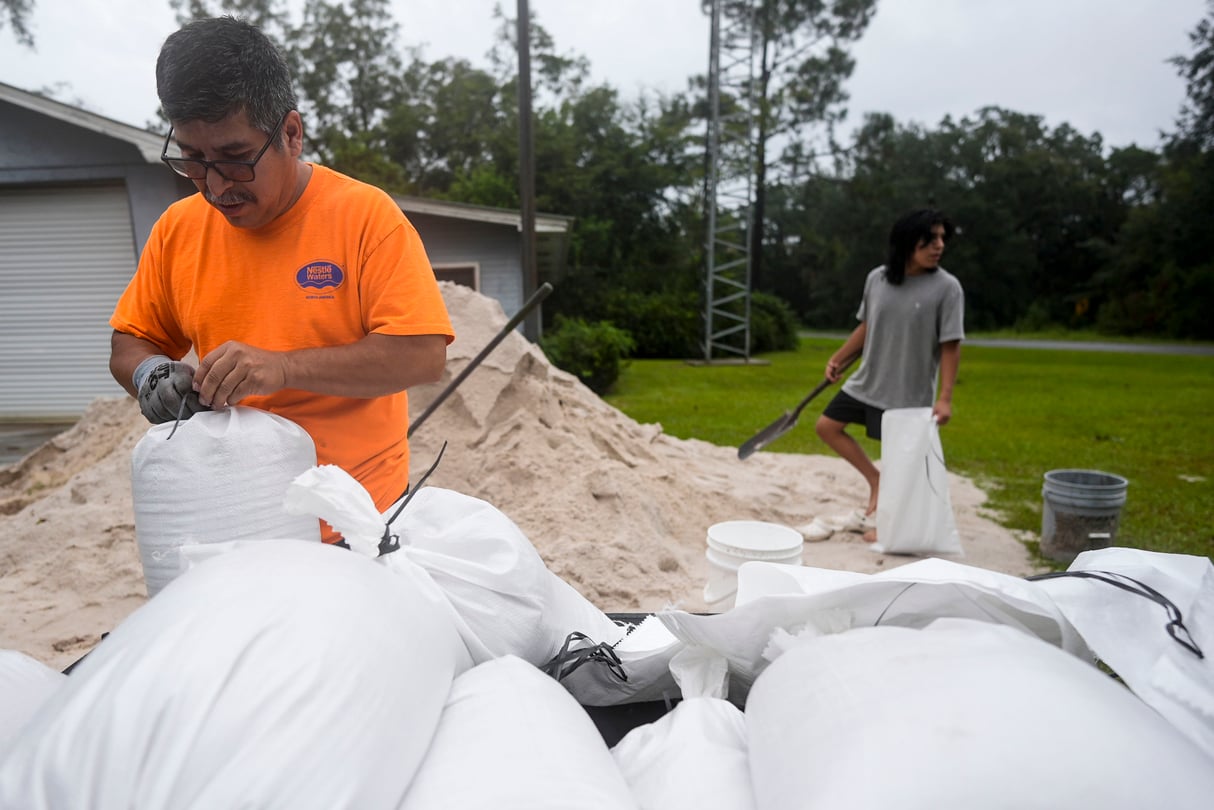 A man and his son fill sand bags on top of a mound of sand.