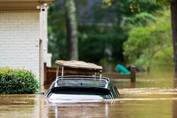 A car is nearly completely submerged outside a home.