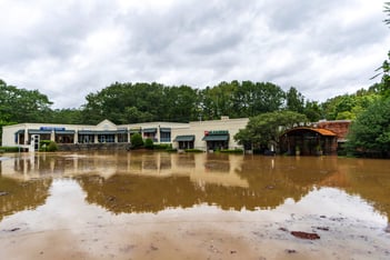Canoe, a restaurant, and a shopping center is surrounded by brown water.