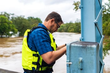 A man wearing a neon vest checks the water gauge above the Chattahoochee River.