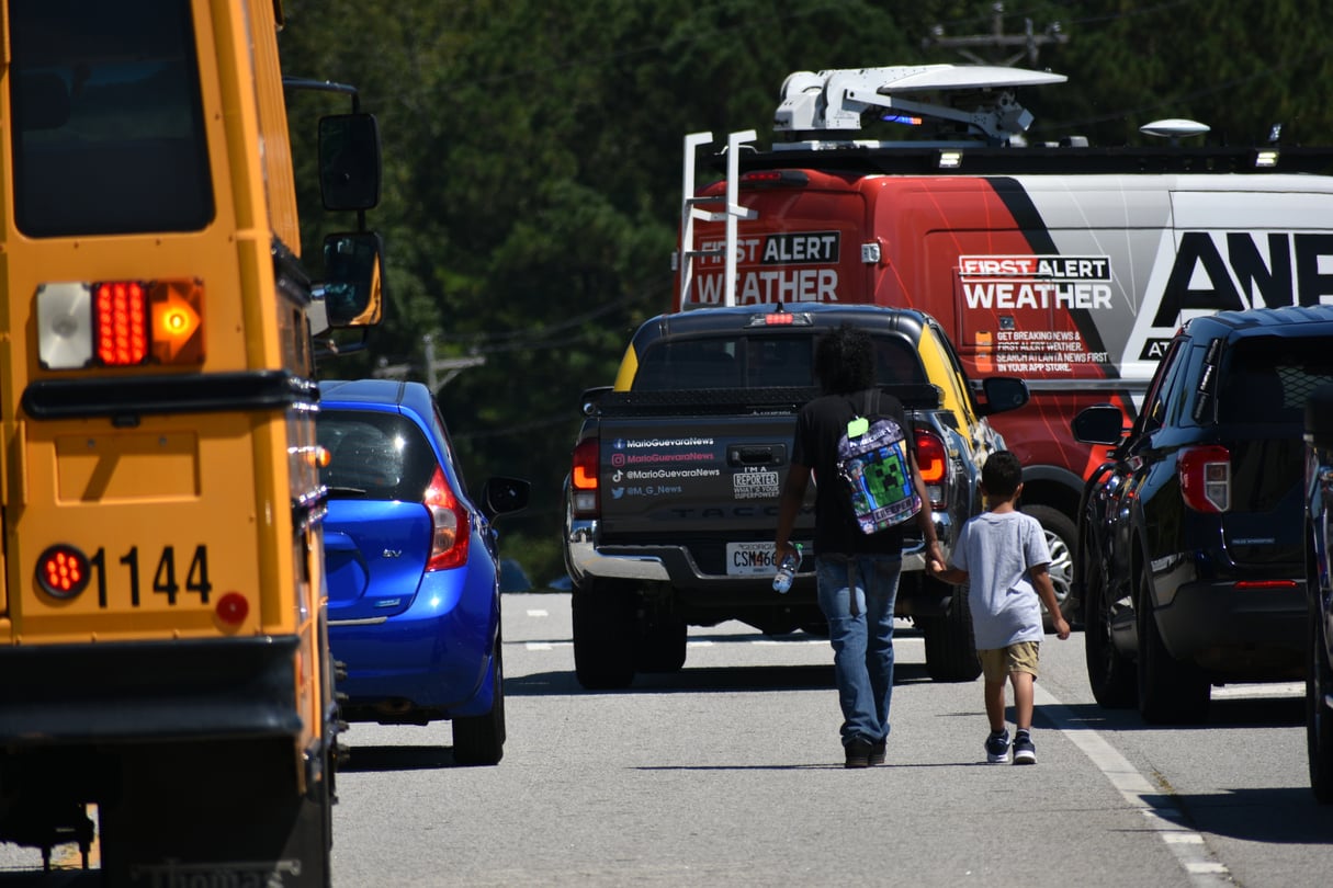 A parent and a child walk near Apalachee High School after a deadly shooting on Sept. 4, 2024.