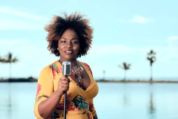 Jessy Diaz holds a microphone in front of a body of water.