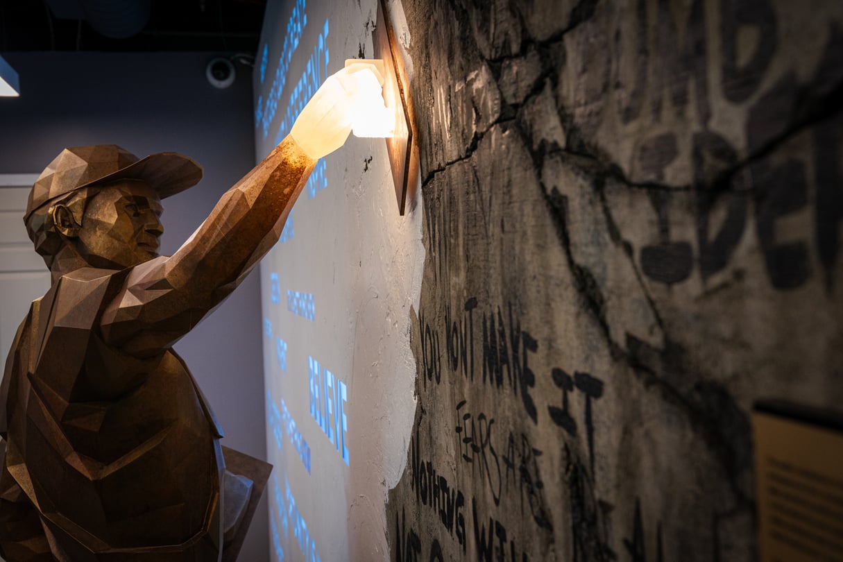 A metal statue of a man plastering on a wall.