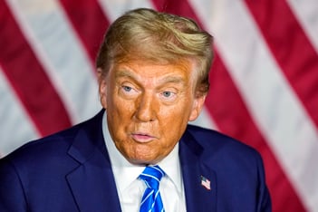 A closeup of Donald Trump's face against the stripes of the American flag.
