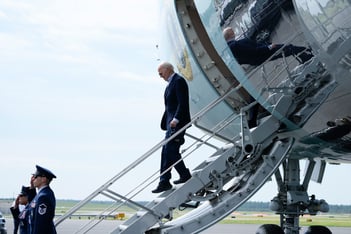 Joe Biden steps down the stairs from Air Force One in an empty lot.