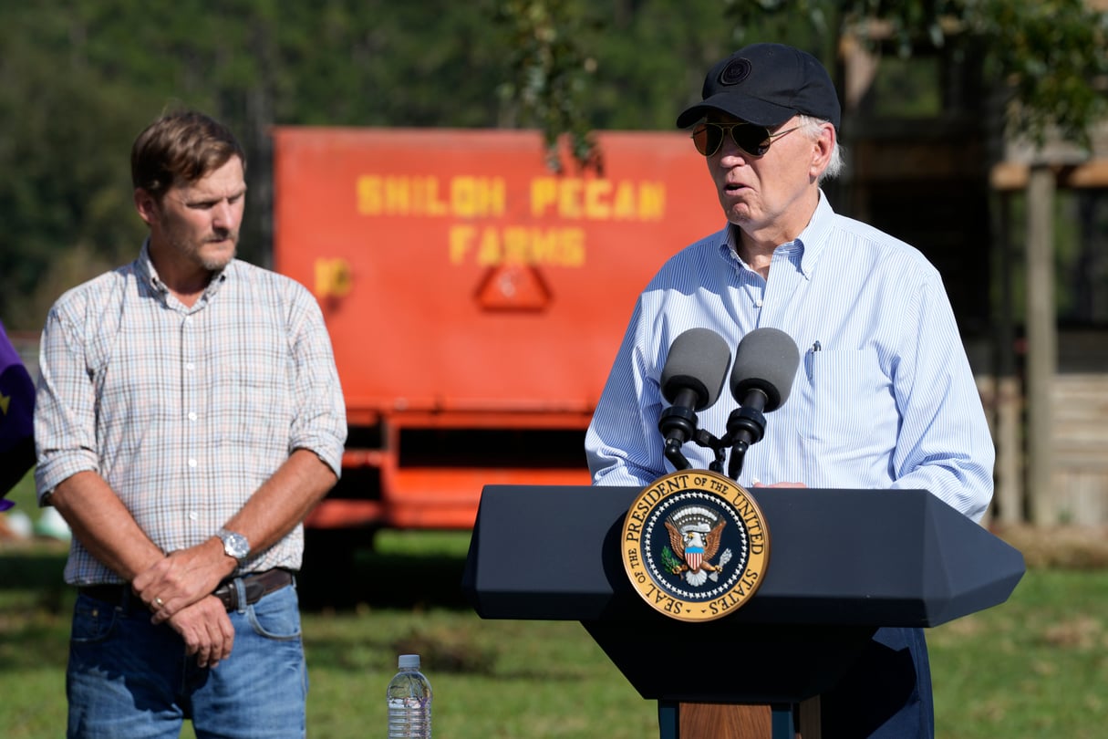 President Joe Biden stands next to Buck Paulk in front of a pecan farm sign, delivering an address.