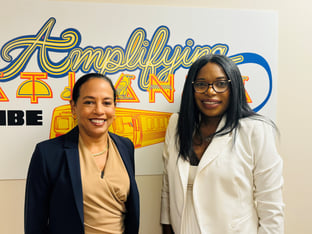 Linder Goler Blount and Tanika Gray Valbrun stand in front of a wall decal that says Amplifying Atlanta.