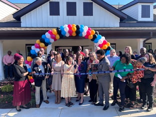 A group of people cut a ribbon in front of the community center.