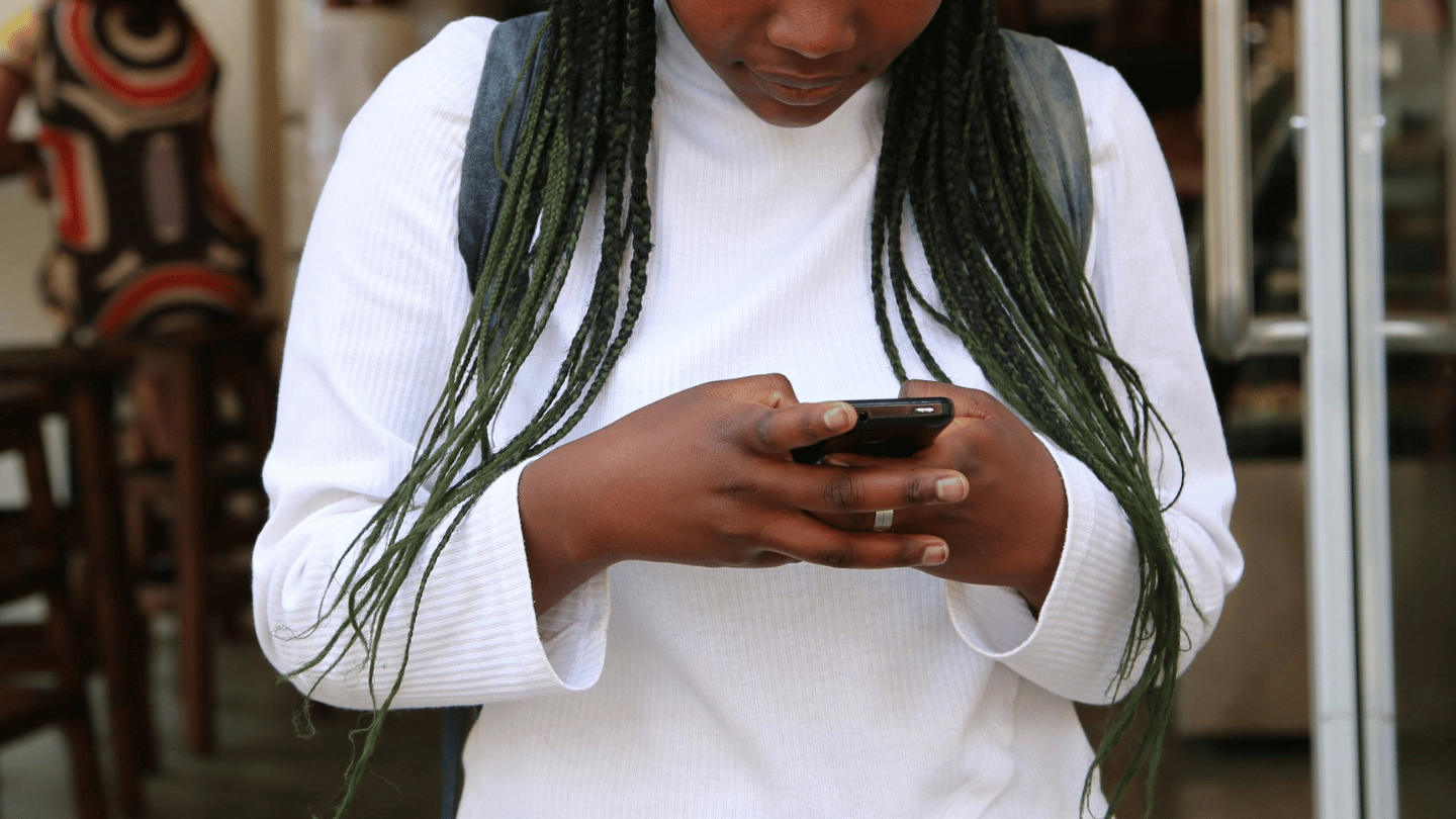 A person wearing a backpack looks down at their phone.