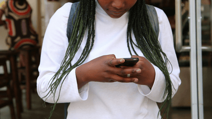 A person wearing a backpack looks down at their phone.