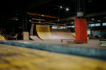 The inside of an indoor skatepark with yellow ramps and dim lighting.