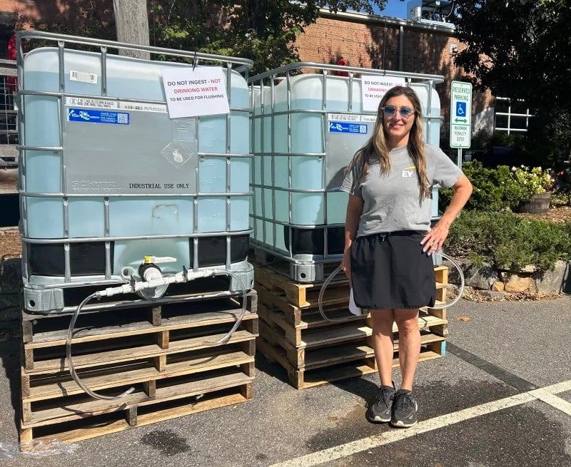 Elle DeBruhl stands next to two gigantic tanks of water.