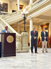 Gabe Sterling speaks at a podium at the Georgia State Capitol. Brad Raffensperger and Blake Evans stand next to him.