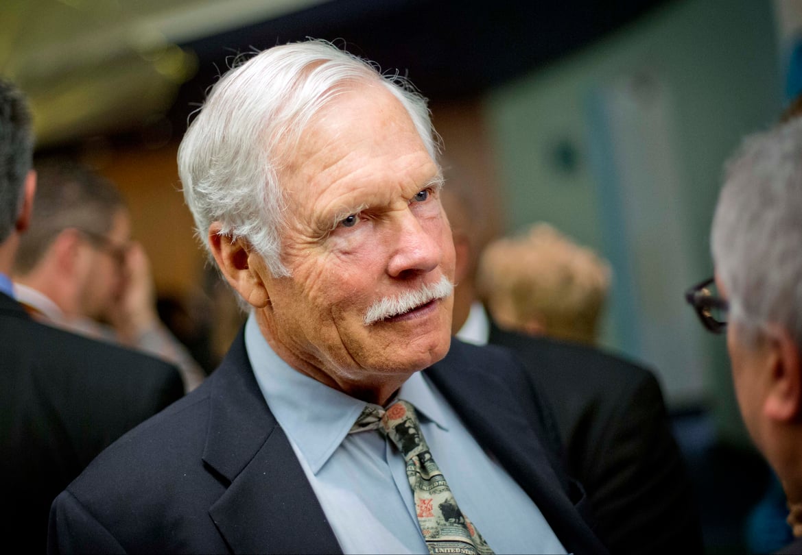 A man with white hair and a mustache in a suit