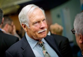 A man with white hair and a mustache in a suit