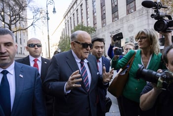 Rudy Giuliani, surrounded by his staff and reporters, arrives at the courthouse.