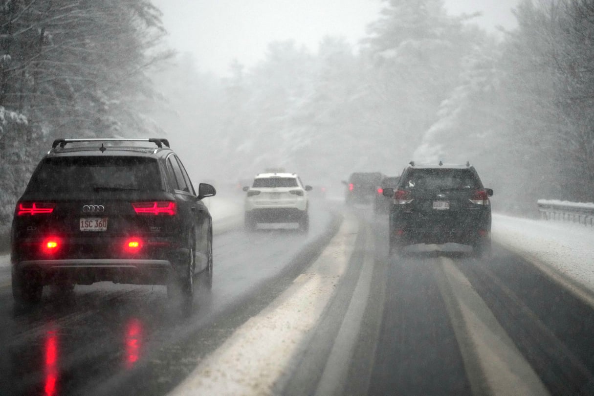 Cars drive through a snowstorm.